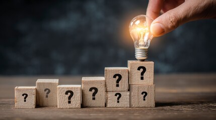 A person places a glowing lightbulb atop a series of wooden blocks, each bearing question marks, symbolizing ideas and problem-solving