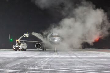 Ground deicing of a passenger jet plane on the night airport at winter