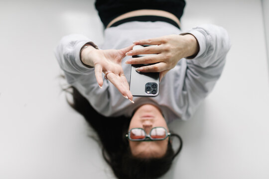 Young woman lying down using smartphone for social media