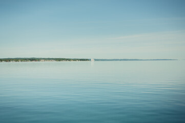Distant sailboat on calm blue water near Traverse City with copy space