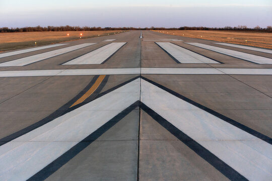 Runway with white directional arrows at dusk on empty airfield