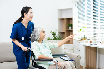 Obraz premium Asian caregiver doctor examine older patient woman therapist nurse at nursing home taking care of senior elderly woman sit on sofa.Medical service concept.
