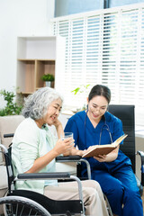 Obraz premium Asian nurse consulting elderly woman in wheelchair at home. Senior care, home healthcare, nursing support, communication and caregiver concept