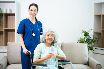 Obraz premium Asian nurse caring for smiling elderly woman in wheelchair at home. Senior care, home healthcare, nursing support, compassion, caregiver service concept