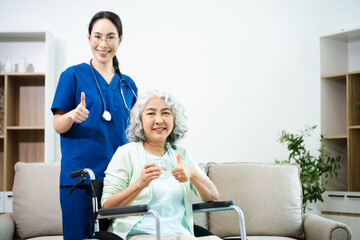 Obraz premium Asian nurse caring for smiling elderly woman in wheelchair at home. Senior care, home healthcare, nursing support, compassion, caregiver service concept