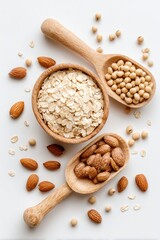 Oatmeal, nuts, and soybeans in wooden bowls and spoons scattered on white
