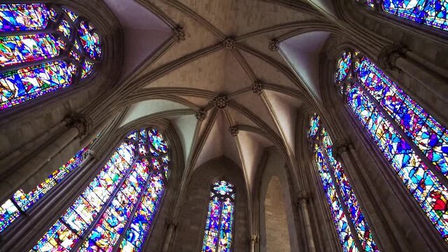 soaring gothic cathedral stained glass windows fill interior with multicolored light ribbed vaults and pointed arches frame intricate tracery and tall clerestory panes closeups reveal painted