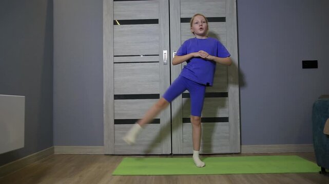 Eight-year-old caucasian girl engaging in daily fitness activity, performing leg lifts and stretches on green yoga mat at home, promoting health and wellness of child