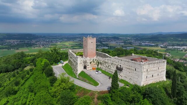 orbiting aerial of the Romeo and Juliet inspirational castle Castello di Giulietta in Vicenza, Italy showcasing the castler perched high on a hill and the surrounding countryside