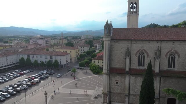 slow rising aerial of Duomo di Santa Maria church in Montecchio Maggiore, Italy, picturesque town view with side of church in perfect view
