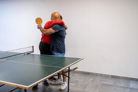 Father and Son Hug After Emotional Ping Pong Game – Indoor Sports Bonding, Generational Connection and Father’s Day Concept - Powered by Adobe