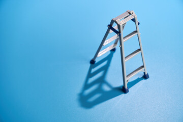 toy ladder against blue background with hard shadow.
