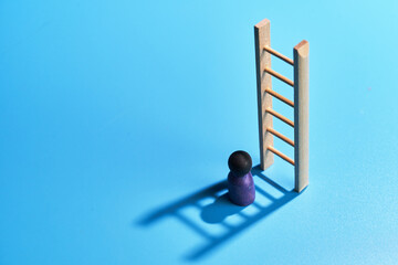 toy ladder and  figurine against blue background with shadow.