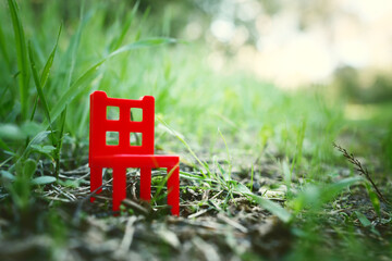 miniature red plastic chair in nature at sunset