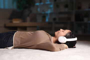 Asian woman listening music from headphone in the night at home