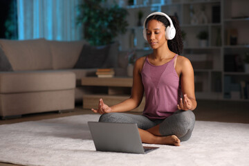 Black woman doing guided yoga class in the night