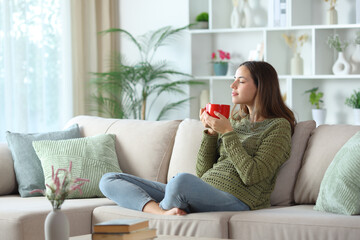 Woman in green relaxing smelling coffee from red cup