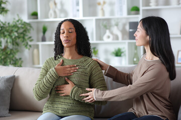 Woman teaching friend to do breathing exercises at home