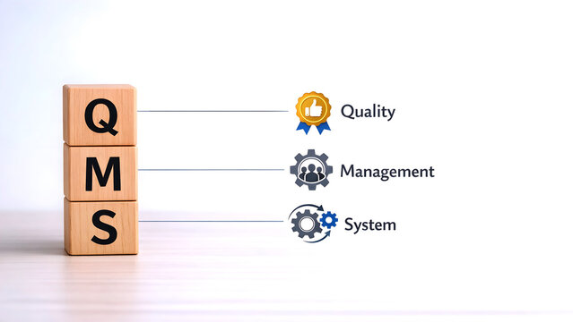 "Wooden cubes displaying QMS symbols highlight the concept of a Quality Management System&mdash;an ISO 9001‑based framework designed to achieve quality objectives."