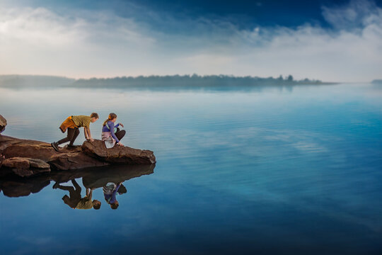 Two Kids Climbing on Rocks overlooking Blue Lake