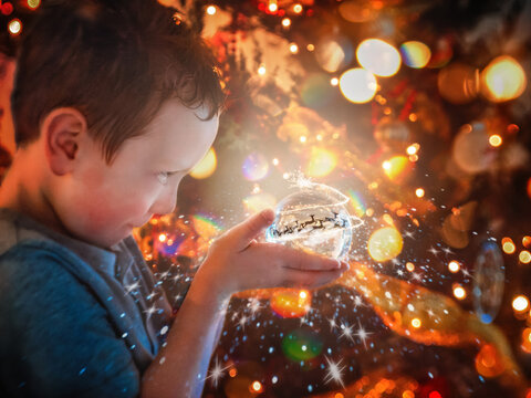 Boy Looking into Snow Globe with Magical Lights