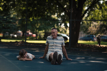 grandpa and grandson relaxing on tennis court at park on summer day
