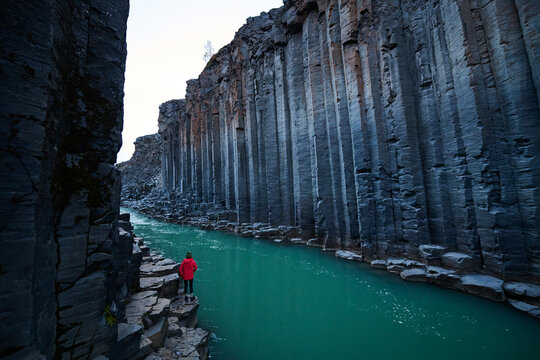 Hiker Dwarfed by Tall Walls in Studlagil Canyon