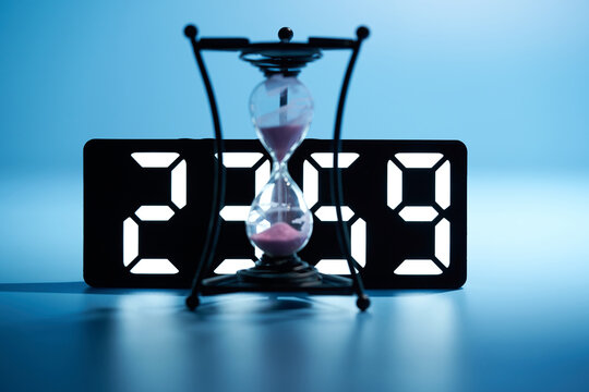 focus on background , midnight 23:59 digital clock with hourglass countdown on blue background - Powered by Adobe