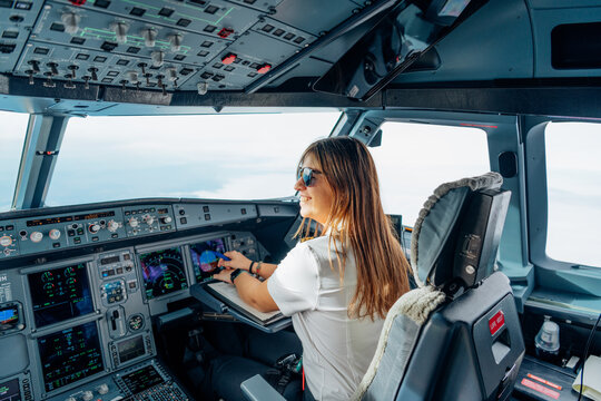 Smiling female pilot operating aircraft controls in airplane cockpit