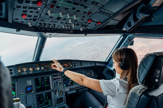 Female airline pilot adjusting autopilot controls in aircraft cockpit