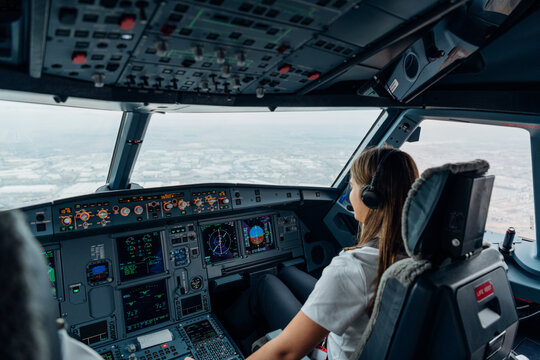 Female pilot operating commercial aircraft cockpit during landing