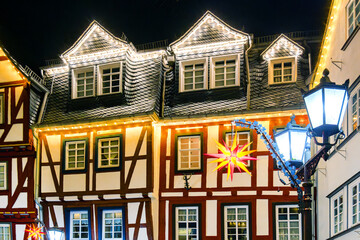 Illuminated half timber facade in Herborn at night with star ornament and lanterns, detailed roof dormers.
