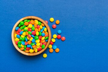 Multicolored candies in a bowl on a colored background. birthday and holiday concept. Top view with copy space
