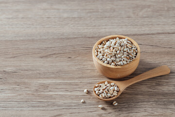 Organic Pearl Barley Grains in Wooden Bowl and Spoon on Table