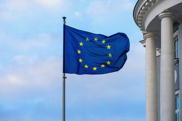 EU flag close up. European Union flag waving in wind near building. Concept of unity, democracy,...