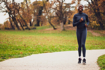 Fototapeta premium A smiling jogger runs on running trail in city park
