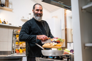 Professional chef is preparing meal in restaurant's kitchen. He makes a vegetarian lunch.
