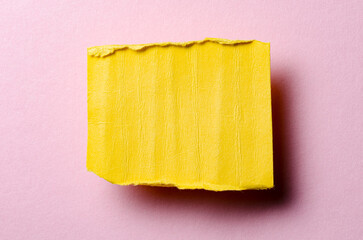 One single yellow torn ripped wrinkled crumpled blank paper note with drop shadow, folded edge and copy space for text on pink background