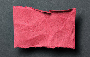 One single red torn ripped wrinkled crumpled blank paper note with drop shadow, folded edge and copy space for text on black background