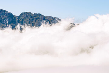 Foggy mountain landscape with clouds covering the lower part of the peak, creating an ethereal and dramatic nature scene for travel and scenic backgrounds.