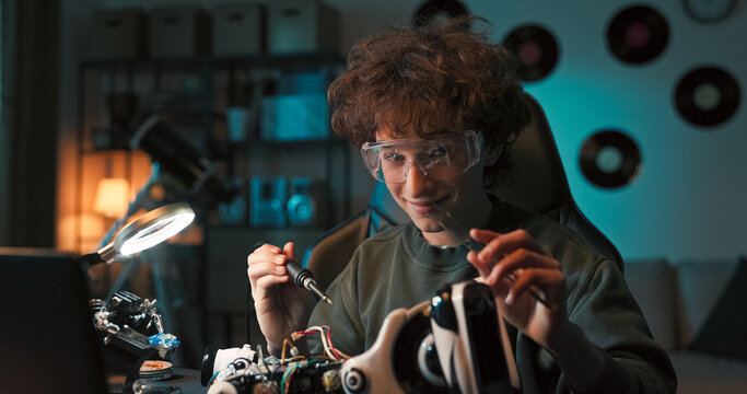 A young student solders small components and repairs wires using tweezers. The hands-on repair of the robot remote builds both confidence and fine motor coordination.
