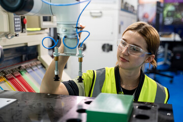 A woman in a yellow vest and goggles is working on a machine