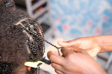 Close-up of hairstylist hands braiding afro hair in detail