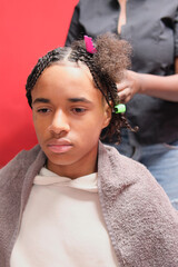 Afro young man with nearly completed braids and a small section left