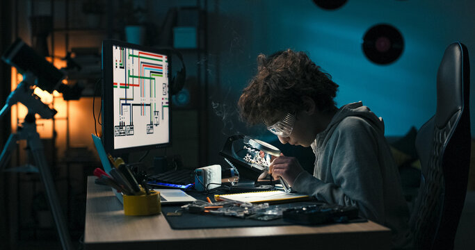 A young learner handles cables and repairs microcomponents using a magnifying glass. He carefully tests each connection, driven by passion for building and fixing devices.