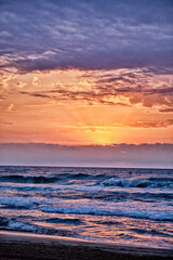 Beautiful sunset over ocean waves with colorful sky during evening hours by the beach