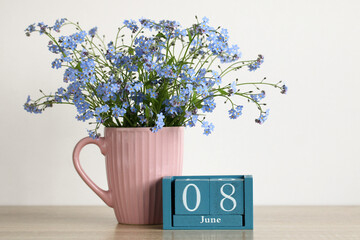 Forget-me-nots blooming in mug with june 8 calendar date