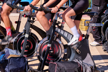 Group of individuals exercising on spin bikes in outdoor fitness class during sunny day