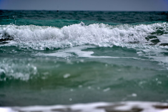 Waves crash on the shore during a cloudy day at the beach, showcasing ocean movements and coastal scenery