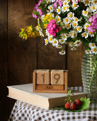 July 19 date on wooden calendar with flowers
